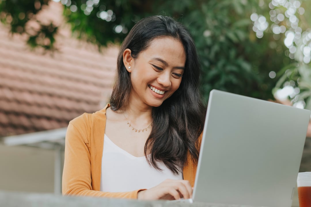 Smiling Woman Using a Laptop Outdoors